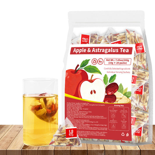 A bag of Apple & Astragalus Tea displayed on a wooden surface next to a glass of brewed tea